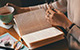 Photo of Open Book with Hand and Cup of Coffee